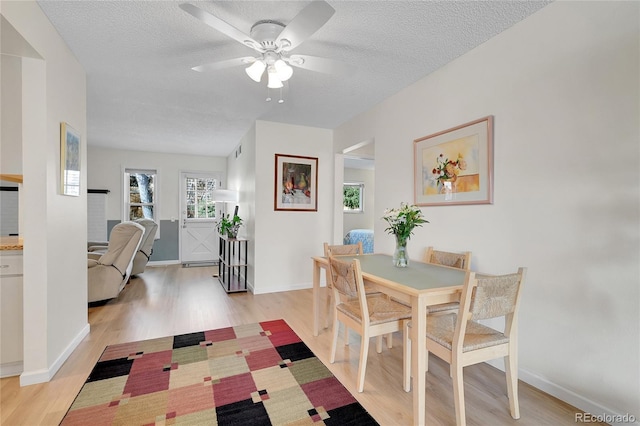 dining space featuring a textured ceiling, light wood-type flooring, and ceiling fan