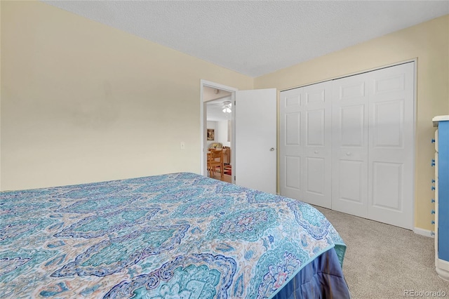 bedroom featuring light colored carpet, a textured ceiling, and a closet