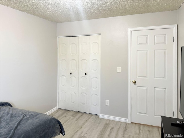 bedroom featuring a textured ceiling, a closet, and light hardwood / wood-style flooring