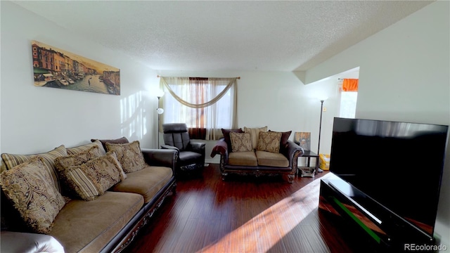 living room featuring dark wood-type flooring and a textured ceiling