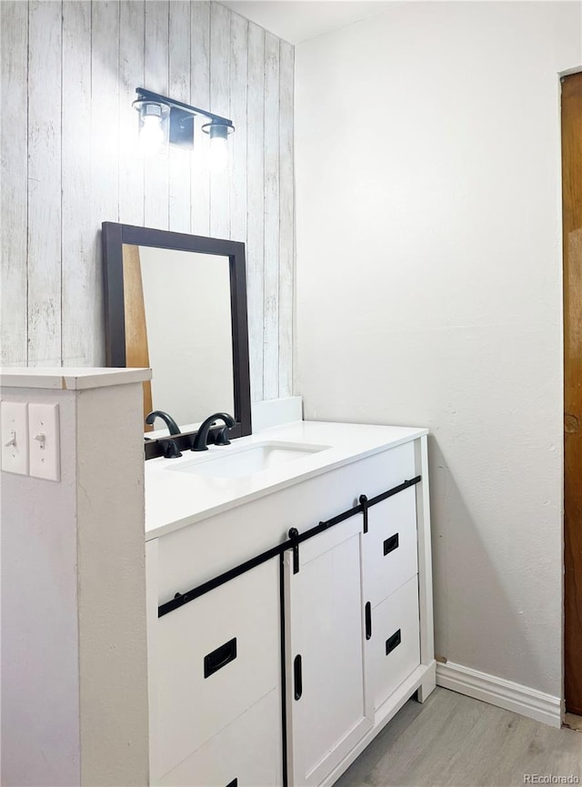 bathroom featuring vanity, wood walls, and hardwood / wood-style flooring