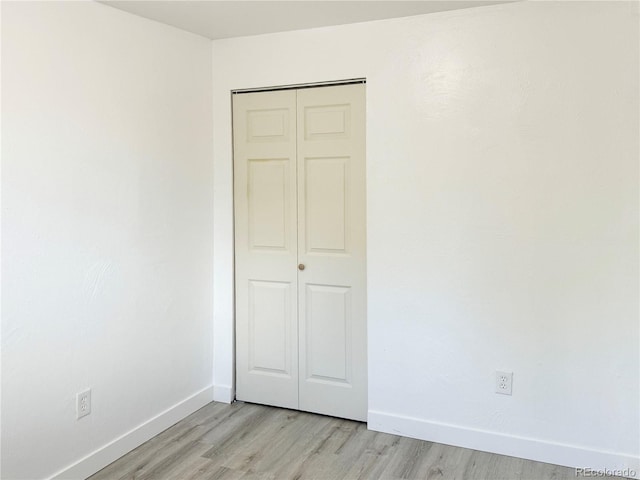 unfurnished bedroom with a closet and light hardwood / wood-style floors