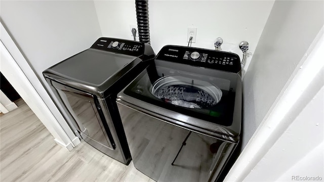 clothes washing area featuring light wood-type flooring and washing machine and dryer