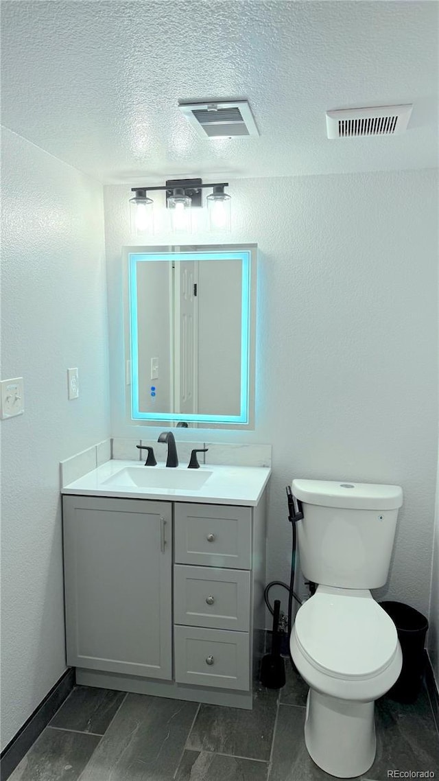 bathroom with toilet, vanity, and a textured ceiling