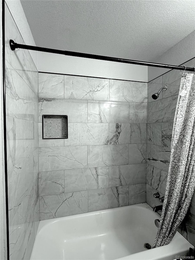 bathroom with a textured ceiling and shower / bath combination with curtain