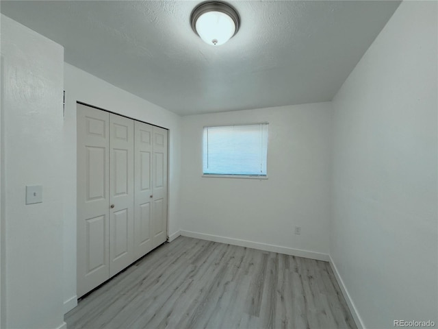 unfurnished bedroom with a textured ceiling, a closet, and light hardwood / wood-style floors