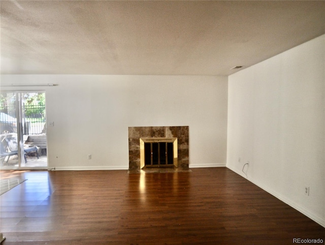 unfurnished living room featuring wood finished floors, baseboards, a premium fireplace, and a textured ceiling