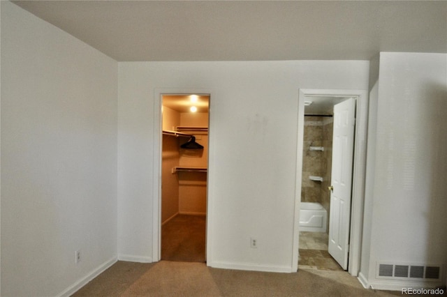 unfurnished bedroom with a walk in closet, carpet, baseboards, and a closet