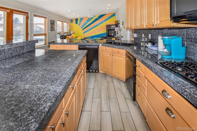 kitchen with decorative backsplash, light hardwood / wood-style floors, kitchen peninsula, black appliances, and ceiling fan