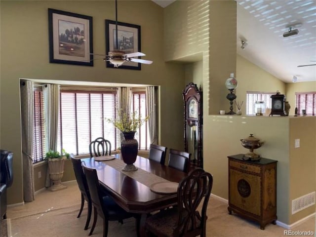 carpeted dining area featuring ceiling fan and high vaulted ceiling