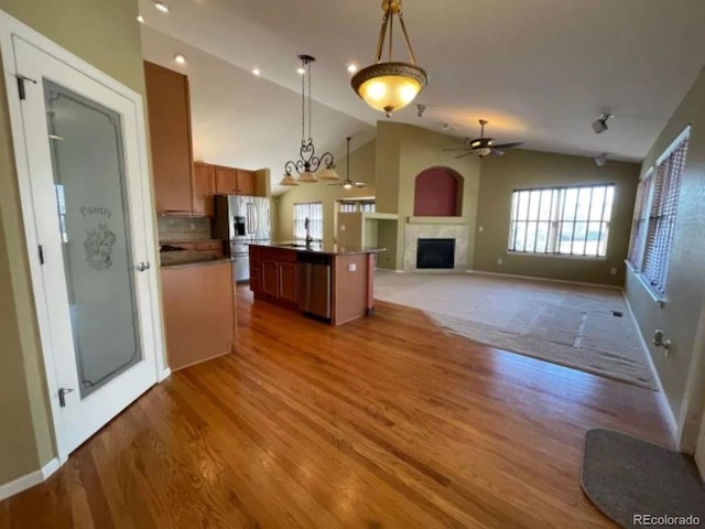 kitchen with ceiling fan, stainless steel appliances, decorative light fixtures, lofted ceiling, and a kitchen island