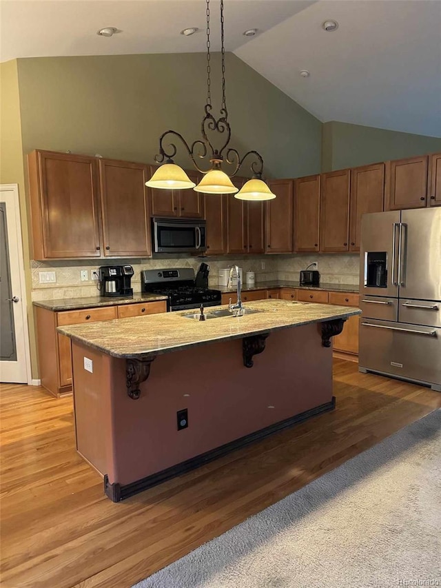 kitchen featuring sink, backsplash, decorative light fixtures, appliances with stainless steel finishes, and hardwood / wood-style flooring