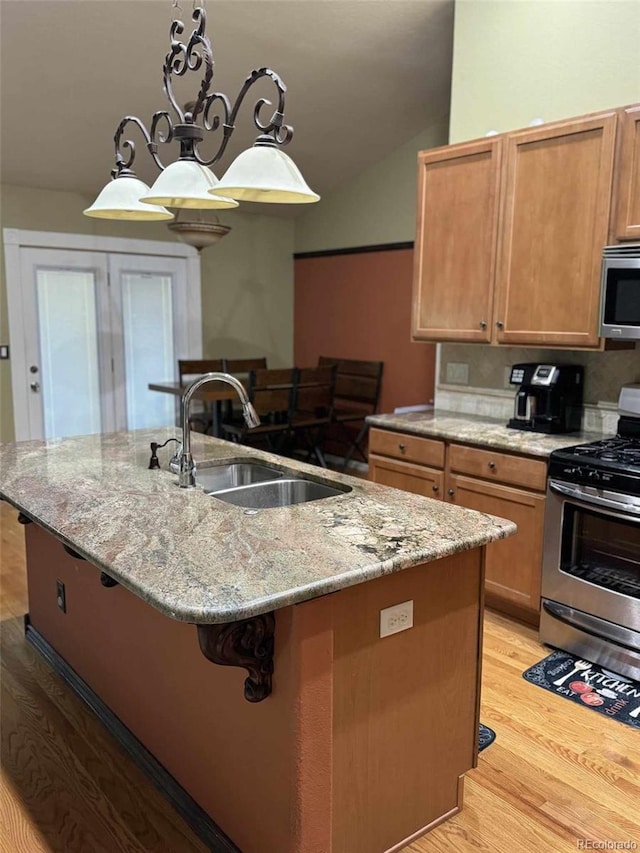 kitchen featuring stainless steel appliances, light hardwood / wood-style flooring, a kitchen island with sink, and sink