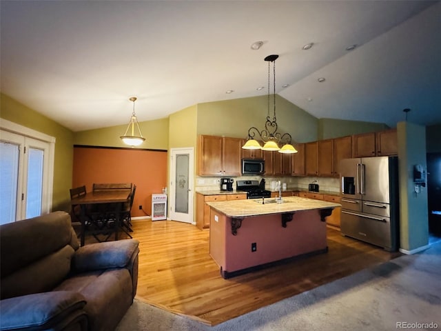 kitchen featuring pendant lighting, stainless steel appliances, a center island with sink, and hardwood / wood-style floors