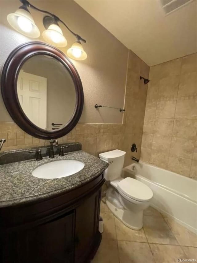 full bathroom featuring tiled shower / bath combo, tile patterned flooring, toilet, vanity, and tile walls