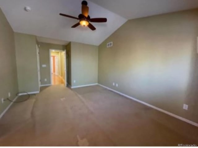 spare room with ceiling fan, light carpet, and vaulted ceiling