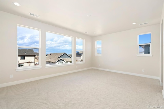 spare room with visible vents, baseboards, and light carpet