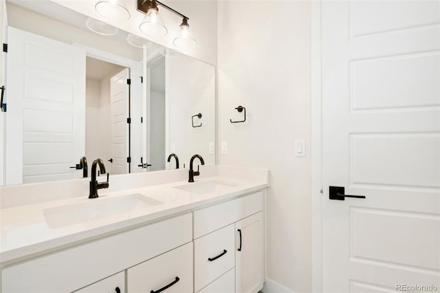 bathroom with double vanity, baseboards, and a sink