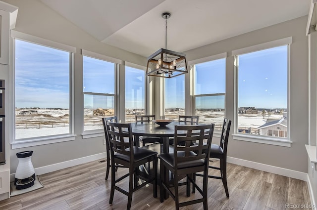 dining area with vaulted ceiling, a notable chandelier, and light wood-type flooring