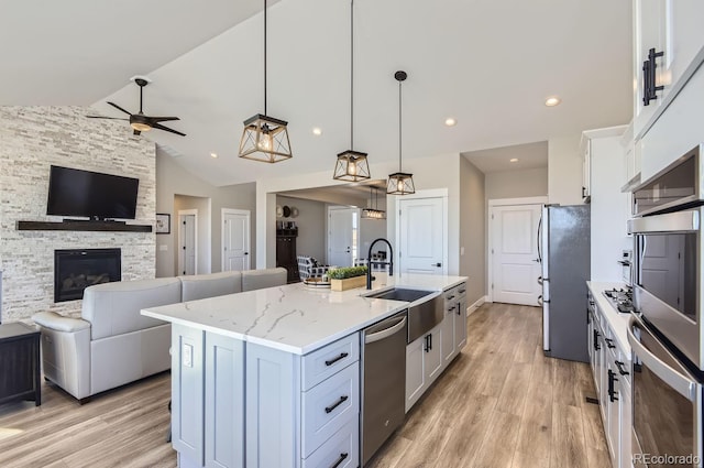 kitchen with white cabinetry, stainless steel appliances, a kitchen island with sink, pendant lighting, and sink