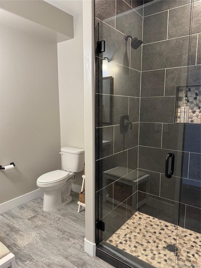 bathroom with toilet, hardwood / wood-style floors, and a shower with door