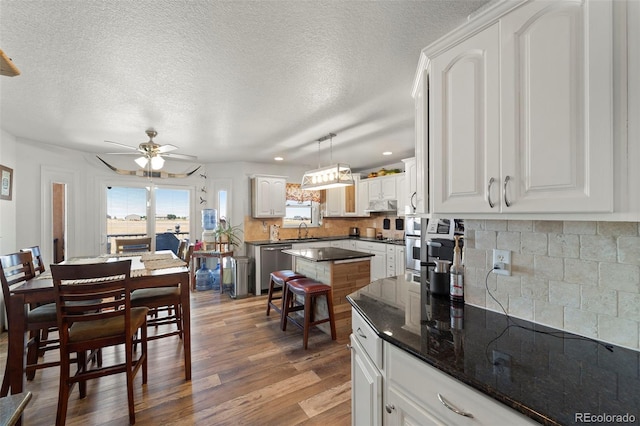 38087 E 147th Pl, Keenesburg, CO 80643 - kitchen featuring under cabinet range hood, a ceiling fan, stainless steel dishwasher, wood finished floors, and white cabinets