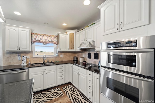 38087 E 147th Pl, Keenesburg, CO 80643 - kitchen with stainless steel appliances, under cabinet range hood, dark wood finished floors, white cabinets, and recessed lighting