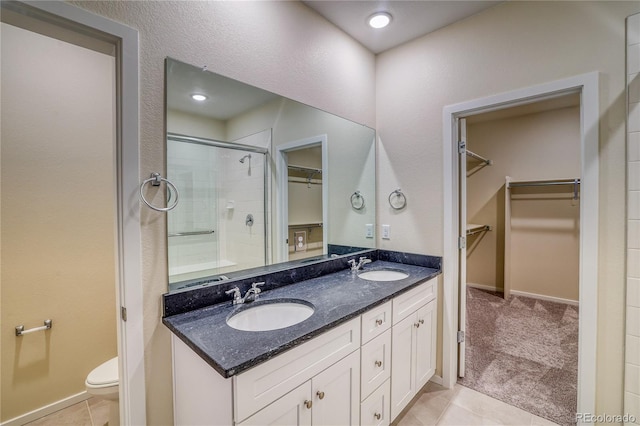 23951 E 40th Ave, Aurora, CO 80019 - full bathroom featuring a stall shower, toilet, double vanity, tile patterned flooring, and a spacious closet