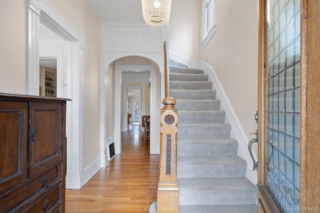 foyer featuring arched walkways, visible vents, baseboards, stairs, and light wood-type flooring