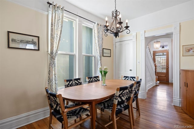 dining space featuring a notable chandelier, arched walkways, and wood finished floors