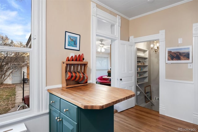 interior space with butcher block countertops, ornamental molding, wood finished floors, blue cabinetry, and ceiling fan with notable chandelier