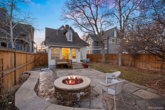 back of property featuring an outdoor fire pit, a chimney, a patio area, and a fenced backyard