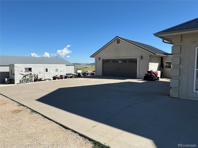 1970 County Road 241, Westcliffe, CO 81252 - view of side of property featuring metal roof, concrete driveway, stucco siding, and a garage