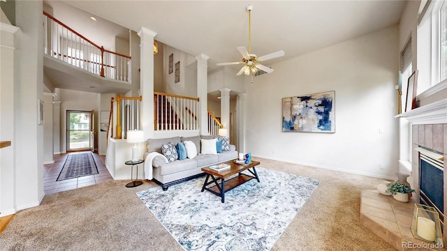 2521 Otter Ct, Lafayette, CO 80026 - carpeted living room featuring ornate columns, ceiling fan, a towering ceiling, stairs, and a tiled fireplace