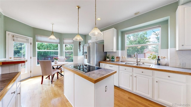 2521 Otter Ct, Lafayette, CO 80026 - kitchen with high quality fridge, dishwasher, white cabinets, black electric cooktop, and light wood-style flooring