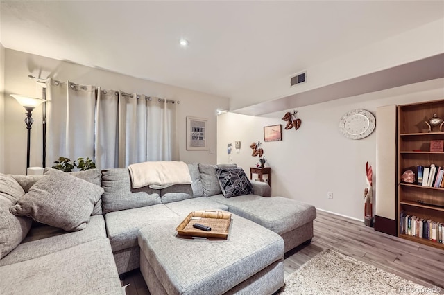 living area with wood finished floors, visible vents, and baseboards