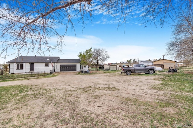 view of front of home featuring a garage, fence, and dirt driveway
