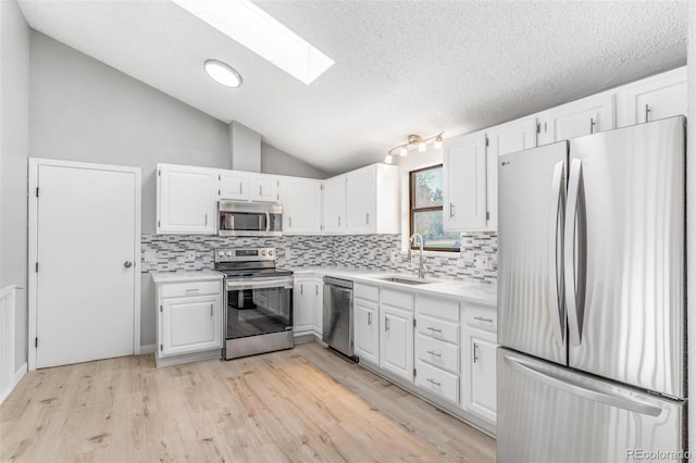 kitchen featuring backsplash, appliances with stainless steel finishes, a sink, and light countertops