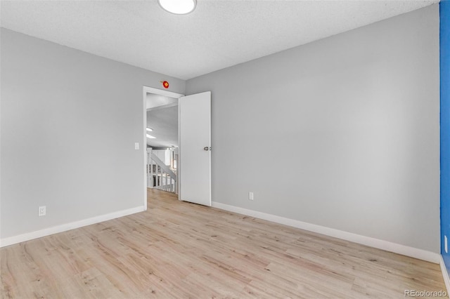 spare room featuring baseboards, a textured ceiling, and wood finished floors