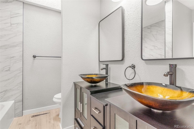 bathroom with a tub to relax in, a sink, visible vents, and toilet