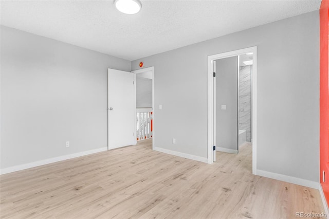 unfurnished bedroom with a textured ceiling, baseboards, and light wood-style floors