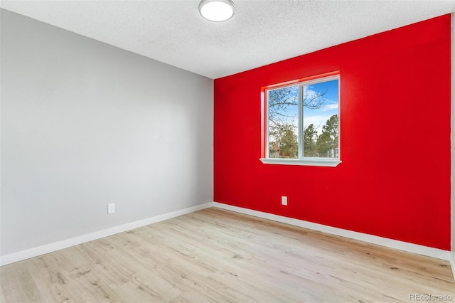 empty room featuring baseboards, a textured ceiling, and wood finished floors
