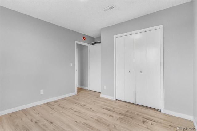 unfurnished bedroom featuring baseboards, wood finished floors, and visible vents