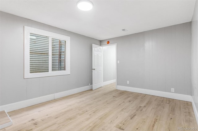 empty room with baseboards, wood finished floors, and visible vents