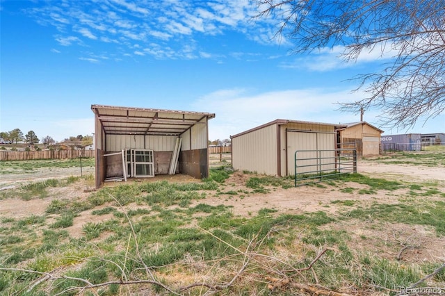view of pole building featuring fence, a detached carport, dirt driveway, and an exterior structure