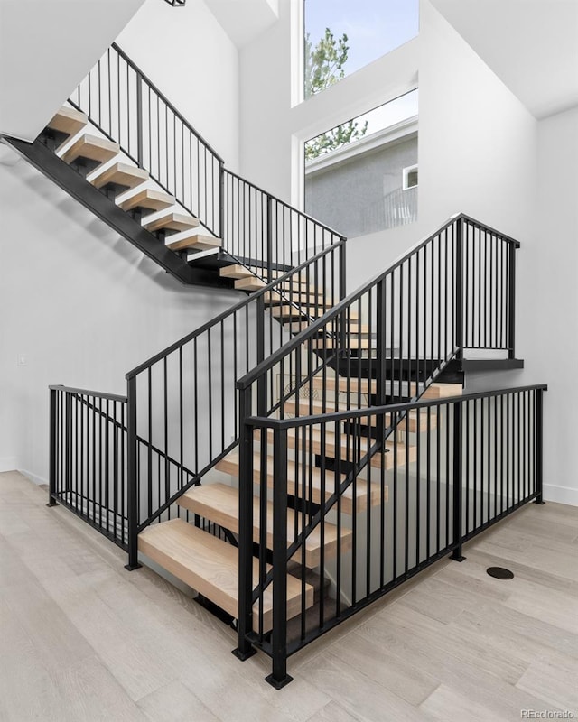 stairs with light hardwood / wood-style flooring and a high ceiling