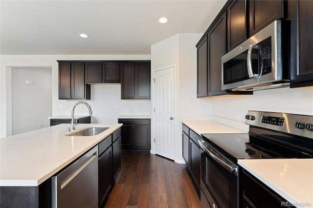 kitchen with stainless steel appliances, dark hardwood / wood-style flooring, sink, a center island with sink, and dark brown cabinetry