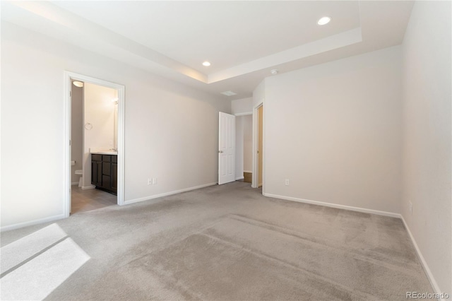 spare room featuring a tray ceiling and light colored carpet