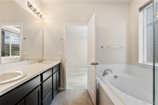 bathroom featuring tile patterned flooring, vanity, and tiled tub