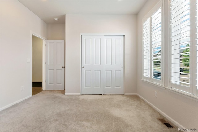 unfurnished bedroom with a closet, multiple windows, and light carpet